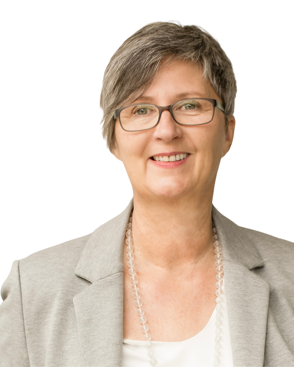 Frau mit kurzen grauen Haaren, Brille und blasser Bluse, lächelt freundlich.